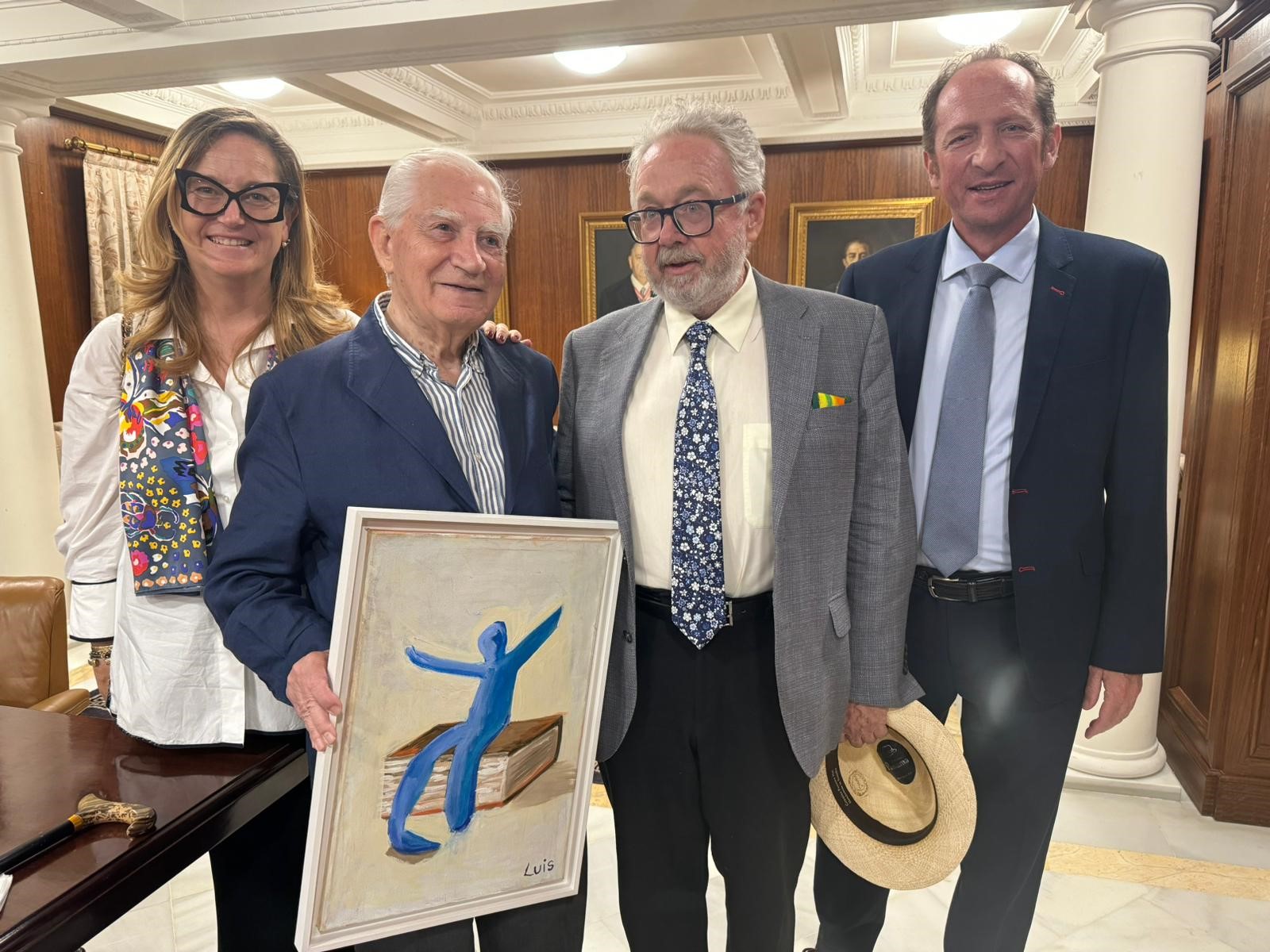El notario honorario Rafael Leña sostiene el cuadro original, base del nuevo diseño; acompañado de varios miembros del equipo de la Fundación Aequitas: De izquierda a derecha: Almudena Castro-Girona (directora); Luis Giménez-Villanueva (notario de Huelva y colaborador) y Federico Cabello de Alba (director del Área Social y Económica).